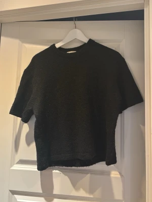 Svart stickad t-shirt - En svart stickad t-shirt med korta ärmar och rund hals. Den är från Gina i storlek M skriv om du har frågor eller vill diskutera pris❤️