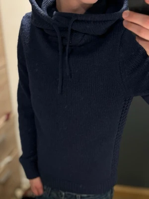 Mörkblå stickad hoodie - Säljer en mörkblå stickad hoodie med huva och dragsnören. Skicket är mycket bra, Storlek S