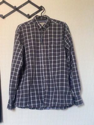 Rutig blå skjorta från MURREY - Snygg rutig skjorta i blått och vitt från MURREY Skjortan har klassisk krage, knäppning framtill och en bröstficka. Perfekt för en avslappnad och stilren look. Långärmad och i mjukt bomullsmaterial.