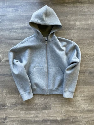 Grå hoodie med dragkedja från Weekday - Grå hoodie från Weekday i storlek S. Tröjan har dragkedja med 2 olika zippar på plus en stor huva och är en allmänt skön tröja. Modellen heter ”weekday scuba”. Skriv vid frågor! Nypris är 650kr