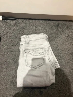 Grå bootcut jeans med fickdetaljer från Gina  - Snygga grå bootcut jeans med fickor bak som har lock och knapp. De är från gina oxh säkjrr då jag inte använder dem längre. Köpta för 500, väldigt bra skick och använda tre gånger 