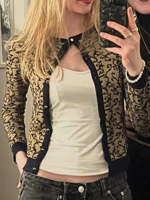 Mönstrad kofta från Holly White - Snygg guldig kofta med svart mönster från Holly White. Perfekt för att piffa upp en outfit!💕