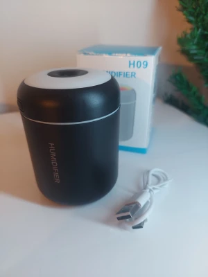 Svart luftfuktare H09 med LED-ljus - Kompakt svart luftfuktare i cylinderformad design med vitt lock och inbyggd LED-belysning som skiftar färg. Drivs via USB och levereras med laddkabel. Perfekt för skrivbordet eller sovrummet för bättre luftfuktighet.