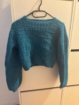 Handstickad blå tröja med grov struktur  - Mysig handstickad tröja i en härlig blå färg. Tröjan har en grovstickad struktur, rund halsringning och långa ärmar. Perfekt för kyliga dagar och enkel att matcha med jeans eller kjol.