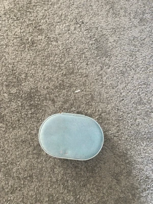 Ljusblå oval smyckesväska - Snygg och kompakt ljusblå smyckesväska i oval form med mjukt material och beige insida. Perfekt för att organisera ringar, örhängen och små accessoarer. Flera fack och elastisk ficka i locket.