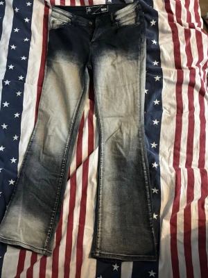 Bootcut jeans från KappAhl, svart/grå - Bootcut jeans  svart och grått med snygg faded effekt. Klassisk femficksmodell med låg midja och utsvängda ben. Jeansen har slitna detaljer och kontrastsömmar för en cool look. 
