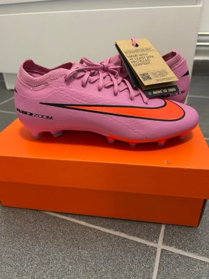 Nike pro Air Zoom rosa fotbollsskor - Zm vapor 16 mercurial pro fg Nike. Skorna är köpta på originalpris av 1999kr. Säljer då de inte passar ,de har prislapp på och är jättesnygga. De är i storlek 39 dam och herr och har låg strumpa och premium comfort, info finns på sista sidan av bilderna . Ställ gärna frågor eller om bilder. Pris kan diskuteras.