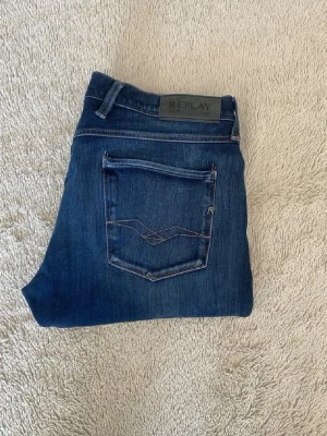 Mörkblå Anbass jeans från Replay - Snygga mörkblå skinny jeans från Replay med klassiska fem fickor och diskreta slitningar. Jeansen har en smal passform och är tillverkade i stretchigt denimtyg för extra komfort. Bakfickorna har dekorativa sömmar och Replay-logga på linningen.