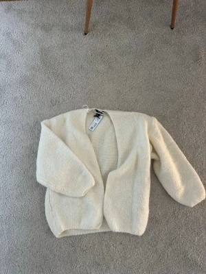 Beige stickad cardigan Lindex  - Aldrig använd och kommer med prislapp!!! Säljer pga köpte dubbelt. Mysig och fluffig beige stickad cardigan från Lindex 🤍🤍🤍🤍