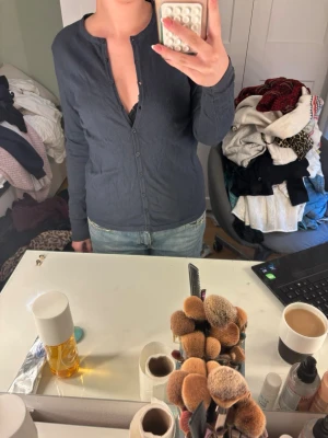Mörkblå basic cardigan - En enkel mörkblå cardigan med rund halsringning och knäppning framtill. Tröjan har lång ärm och är tillverkad i ett mjukt, tunt material som passar perfekt till jeans eller kjol. Stilren och lätt att matcha med olika outfits. Skulle säga M/S
