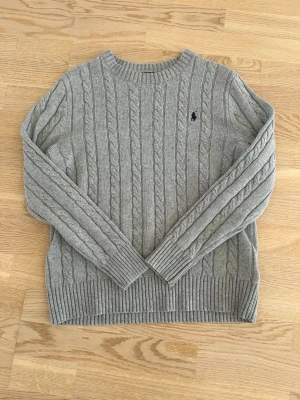 Grå kabelstickad tröja Polo Ralph Lauren - Snygg grå stickad tröja från Polo Ralph Lauren. Helt ny och oanvänd. 