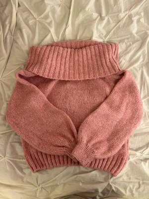 Rosa stickad tröja - Super söt och mysig rosa stickad off shoulder med bred ribbad krage och muddar. Tröjan har en avslappnad passform och långa ärmar, perfekt för kyliga dagar. 