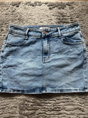 Blå jeanskjol från Miss Bonbon -  Säljer en supersnygg ljusblå jeanskjol från Miss Bon som passar till typ allt i garderoben! Den har en klassisk modell med fickor fram och bak, snygg tvätt och lite rå kant nertill som ger den en cool vibe. Perfekt till sommaren med ett linne och sneakers eller med strumpbyxor och boots när det är kallare. En riktig garderobsfavorit! 📏 Midja ca 34 cm (platt mått) och längd är 37,5 cm  👖 lågmidja  ✨ Mycket bra skick  Säljs då den tyvärr inte kommer till användning längre!💞