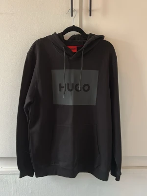 Svart hoodie från HUGO - Svart hoodie från HUGO med stor logga framtill. Den är i nyskick, endast använd 1 gång. 
