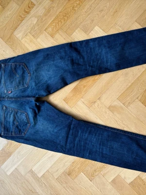 Mörkblå Levi's jeans straight fit - Säljer ett par klassiska mörkblå jeans från Levi's med raka ben och femficksmodell. Jeansen har snygga kontrastsömmar och den ikoniska röda Levi's-lappen på bakfickan. 