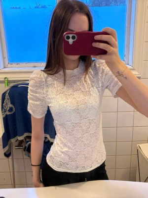 Vit spetsblus från Bik Bok - Säljer en vit spetsblus från Kappahl med korta puffärmar och hög hals. Blusen är helt i spets och har en feminin och elegant look som passar perfekt till jeans eller kjol. och designen är figurnära.