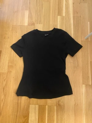 Svart topp med knyt i ryggen - Cool svart topp från Gina tricot med korta ärmar och unik öppen rygg med knytband. 