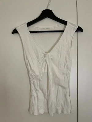 Vitt linne med knutdetal - Snygg vit topp med v-ringning och knutdetalj framtill. 