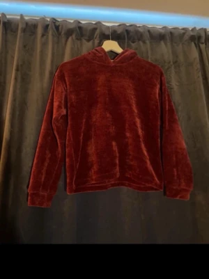 Vinröd velour hoodie - Mysig vinröd hoodie i mjuk velour med huva och långa ärmar. Perfekt för dig som gillar en chill och trendig stil. Ingen synlig logga eller tryck, enkel och clean design. Passar till både jeans och mjukisbyxor.