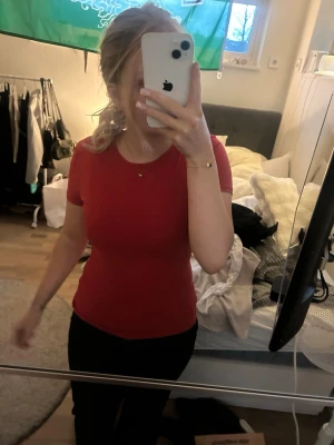 Röd tight kortärmad topp - Enkel och stilren röd topp med tight passform och korta ärmar. Perfekt att matcha med jeans eller kjol för en clean look. T-shirten har rund halsringning och är gjord i ett mjukt material som sitter skönt mot kroppen.