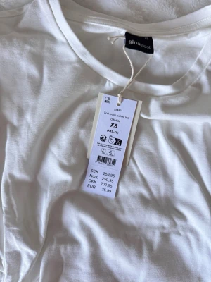 Vit soft touch t-shirt Gina Tricot - Superskön vit t-shirt från Gina Tricot i soft touch-material som känns som ett andra lager hud. Klassisk rund halsringning och korta ärmar. Perfekt basplagg till garderoben och enkel att styla med allt. Aldrig använd prislappen kvar. 