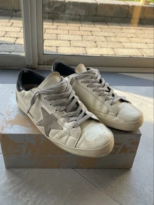 Vita Golden Goose skor - Säljer ett par riktigt feta vita golden goose skor i storlek 44. De är i använt skick. Värt att notera att sulan har gått lite sönder, varav priset, men det är inget man märker med dem på. Skorna är sjävklart äkta och skokartong kommer med! Priset går att diskutera och det är bara att höra av vid funderingar🙌