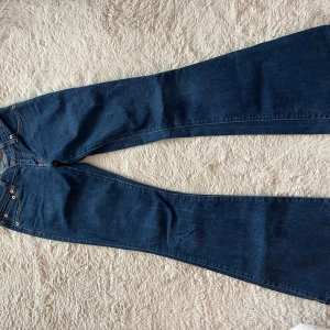 Mörkblå bootcut jeans från Levi's - Snygga mörkblå bootcut jeans från Levi's med klassiska fem fickor och kopparfärgade nitar. Jeansen har en något utsvängd passform nedtill och är tillverkade i kraftig denim. Perfekta för dig som gillar en tidlös och avslappnad stil.