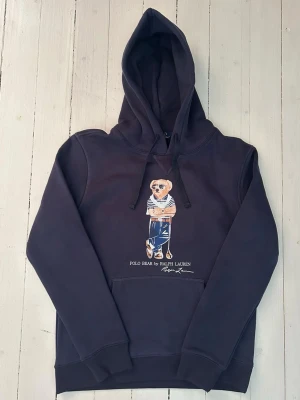 RalphcLauren polo bear hoodie herr, storlek S  - Hej! Säljer denna riktigt schyssta hoodie från Ralph Lauren. Den är i storlek M men sitter en storlek litet och passar därför som en S. Den är endast använd någon enstaka gång och är därmed i ett nyskick. Original lappar och påse finns kvar och medföljer naturligtvis vid köp. Jag fraktar alltid snabbt! Mvh