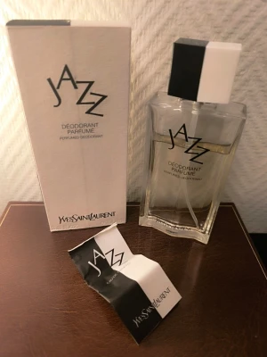 YSL Jazz Déodorant Parfumé 100ml — vintage - Jazz lanserades 1988 och är ett klassiskt herrdoft som blivit svårare att hitta i det här skicket. Passar samlaren eller den som minns originalet. Lådan har normalt åldersslitage. Flaskan är i fint skick.