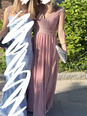 Ljusrosa balklänning - Jättefin balklänning i ljusrosa med spetsdetaljer upptill och v-ringad hals. Dragkedja vid ryggen som man drar upp och inga defekter förutom att den är lite smutsig nertill men som går bort vid tvätt. 