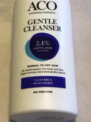 ACO Gentle Cleanser 300ml - Mild rengöring för normal till torr hud från ACO. Innehåller 2,4% mjölksyra och glycerin som återfuktar och rengör både ansikte och kropp. Vegansk formula, parfymfri och dermatologiskt testad. Vit plastflaska med blå och lila detaljer.