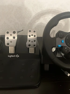 Logitech G29 ratt och pedaler - Säljer en Logitech G29 racingratt med pedaler, perfekt för PlayStation och PC. Ratten har svart läderklädsel, blå detaljer och flera knappar för gaming. Pedalerna är i metall och plast, med gas, broms och koppling. Grym för racing och simracing! Saknar laddare man kan köpa för 250kr i cdon