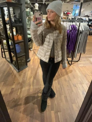 Beige pufferjacka från Herno - Snygg beige pufferjacka från Herno med rund halsringning och två fickor framtill med knappdetaljer. Jackan har en lätt glansig finish och quiltad design som ger en modern look. Perfekt för kalla dagar när du vill vara både varm och stilren. Köpt för 5000kr 