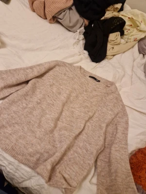 Beige stickad tröja från 157 - Mysig beige stickad tröja från 157 i storlek XS. Tröjan har rund halsringning, långa ärmar och ribbade muddar vid ärmslut och nederkant. Perfekt för lager på lager och enkel att matcha med olika outfits.
