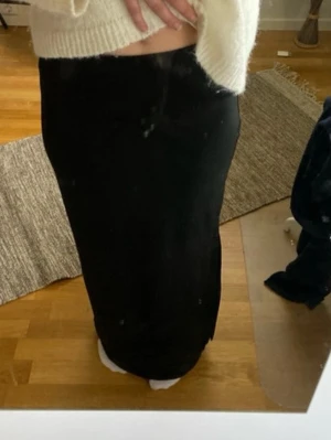 Svart långkjol med slits - Säljer en svart långkjol med slits på sidan. Kjolen har en rak passform och är enkel att matcha med olika toppar. Perfekt för dig som gillar stilrena plagg med en twist.