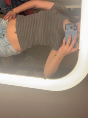 Grå randig croppad topp - Säljer en grå, croppad topp med tunna horisontella ränder. Toppen har rund halsringning och korta ärmar. Perfekt till jeans eller kjol för en avslappnad look.