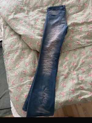 Blå bootcut jeans med slitningar - Säljer ett par blå bootcut jeans med  ljusa partier framtill. Jeansen har låg midja. Perfekta för dig som gillar en retro och avslappnad stil. Jag är 179cm lång. Storlek är W29 L34!