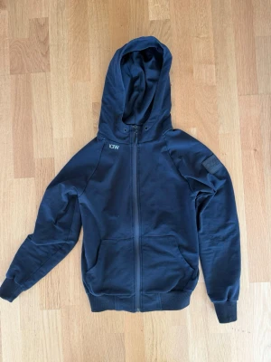 Svart hoodie från ICANIWILL - Svart hoodie med dragkedja från ICANIWILL. Klassisk modell med huva, två fickor framtill och ribbade muddar vid ärmslut och midja. Perfekt för en avslappnad stil. Väldigt skön! Hittar inte storlek men tror S. 
