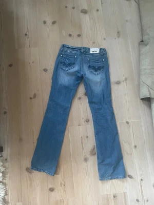 Blå bootcut jeans  - Säljer ett par klassiska blå bootcut jeans från Miss jeans. Jeansen har fem fickor, snygga slitningar och en något utsvängd passform nertill.. Perfekta för en avslappnad och trendig look. 