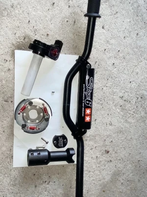 Styre och delar Stage6 till moped - Säljer ett svart styre från voca med tillhörande delar som en röd snabgas, division koppling, styrfäste och lock från str8, perfekt för dig som vill uppgradera eller bygga om din moped. Snygg design med Stage6-logga på barpadden. Styre me barpad 350kr, styrstam 301kr, divison koppling 309kr, snabbgas 99kr