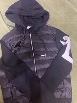 Moncler cardigan - Snygg svart pufferjacka från Moncler med huva och dragkedja framtill. Jackan är ganska ny och oanvänd. Den har även nfc tagg