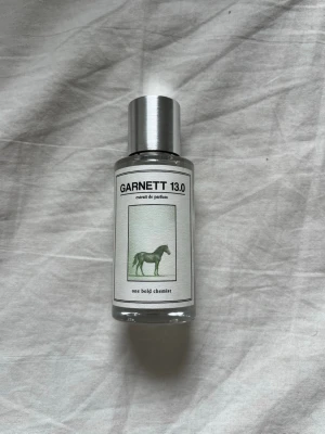 Garnett 13.0 parfym One Bold Chemist - Parfymflaska i glas med silvrig metallkork från One Bold Chemist. Doften heter Garnett 13.0 och är inspirerad av parfums de malry greenly, etiketten har en stilren design med en grön häst. Flaskan är genomskinlig och cylindrisk, vilket ger ett modernt intryck. Har bara spejat 4-7 sprut med den här så är nästan helt ny. 