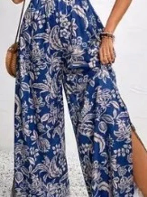 Blå blommig jumpsuit med slits🌸 - Oanvänd Snygg blå jumpsuit med vitt blommönster och vida ben. Materialet känns lätt och luftigt, perfekt för sommardagar. Slits på benen ger en extra cool touch.🧚🏻