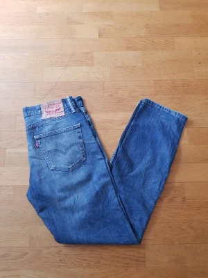 Levi's 511 blå jeans herr - Klassiska blå jeans från Levi's modell 511 med rak passform och fem fickor. Jeansen har en snygg tvättad look, Levi's ikoniska läderpatch bak och röd etikett på bakfickan. Tillverkade i slitstark denim av bomull.
