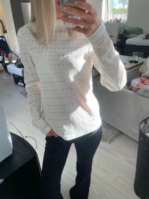 Vit spetsblus med lång ärm - Säljer en vit blus med broderade hålmönster och hög hals. Blusen har som ”scrunch” detaljer på axlarna