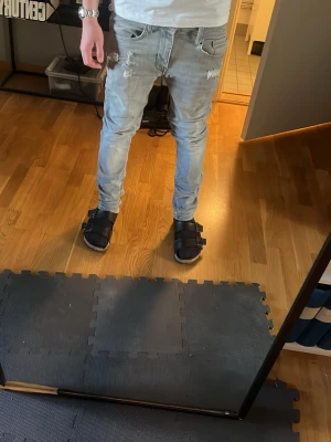 Jack and Jones Slim jeans  - Säljer ett par ljusgrå slim  jeans från Blend med slitningar och trasiga detaljer vid fickorna. Jeansen har klassisk femficksdesign och smal passform. Perfekta för en avslappnad och trendig look.
