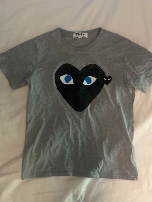 Grå Play t-shirt - Grå t-shirt från Comme des Garçons Play för 350kr. Strlk S och är i perfekt skick.