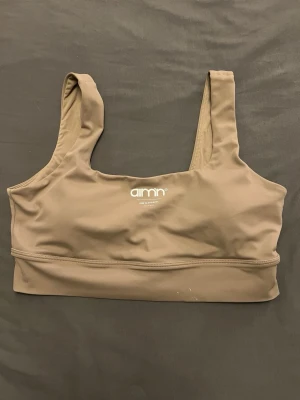 Beige sport-bh från Aim'n - Säljer en beige sport-bh från Aim'n med breda axelband och fyrkantig ringning. Bh:n är tillverkad i ett stretchigt och mjukt material som ger bra stöd. Perfekt för träning eller en aktiv vardag. Diskret logga framtill.