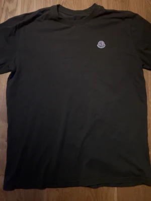 Moncler t-shirt med logga - Snygg brun t-shirt från Moncler med klassisk rund hals och liten Moncler-logga på bröstet. Enkel och stilren design som passar perfekt till jeans eller shorts. Tillverkad i mjuk bomull för skön känsla hela dagen.