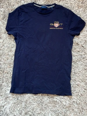 Marinblå t-shirt från Gant - Snygg marinblå t-shirt från Gant. Klassisk rund hals och korta ärmar. 